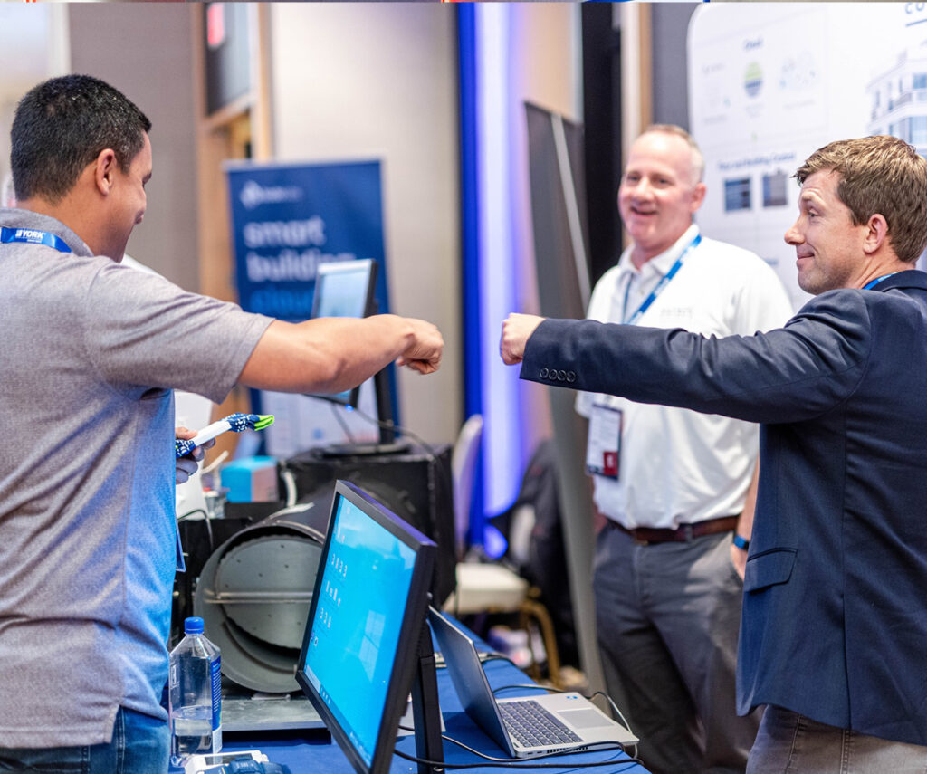 two hvacr contractors fist-bumping at controls-con tradeshow